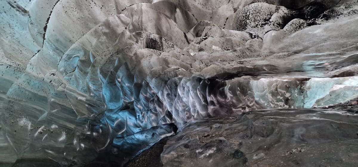 Blue glacier ice with volcanic ash bands inside a natural Vatnajökull ice cave