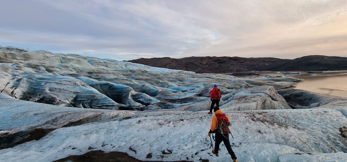 Two guests walking across sculpted glacier ice toward the lagoon on the Adventures Dream tour
