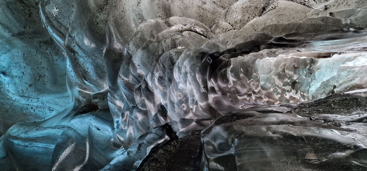Layers of volcanic ash running through the sculpted ice walls of a naturally formed Vatnajökull ice cave